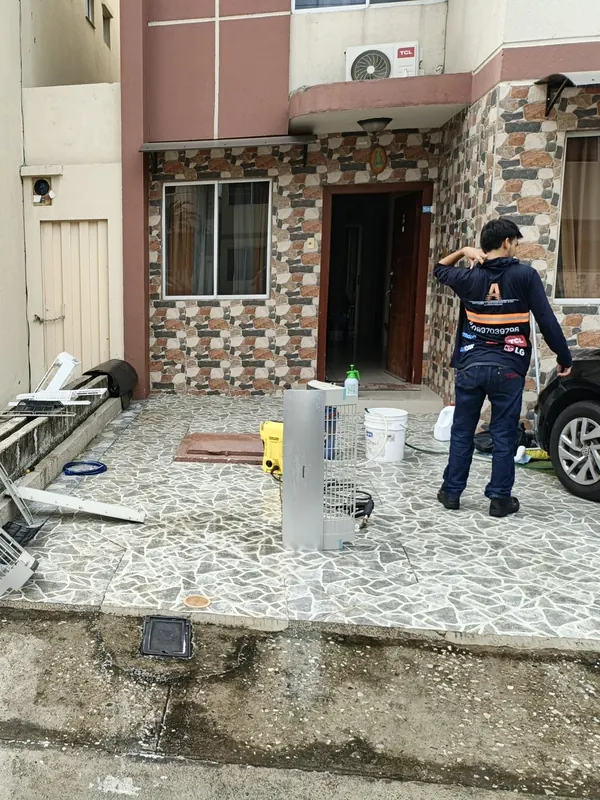 Técnico de Alvarado Solutions limpiando un aire acondicionado con hidrolavadora en el norte de Guayaquil