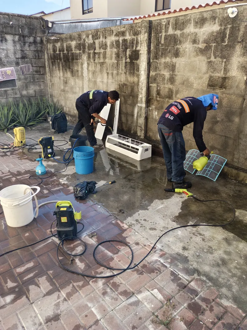 Técnicos de Alvarado Solutions lavando las piezas de un aire acondicionado split con hidrolavadora en Villa Club, La Aurora