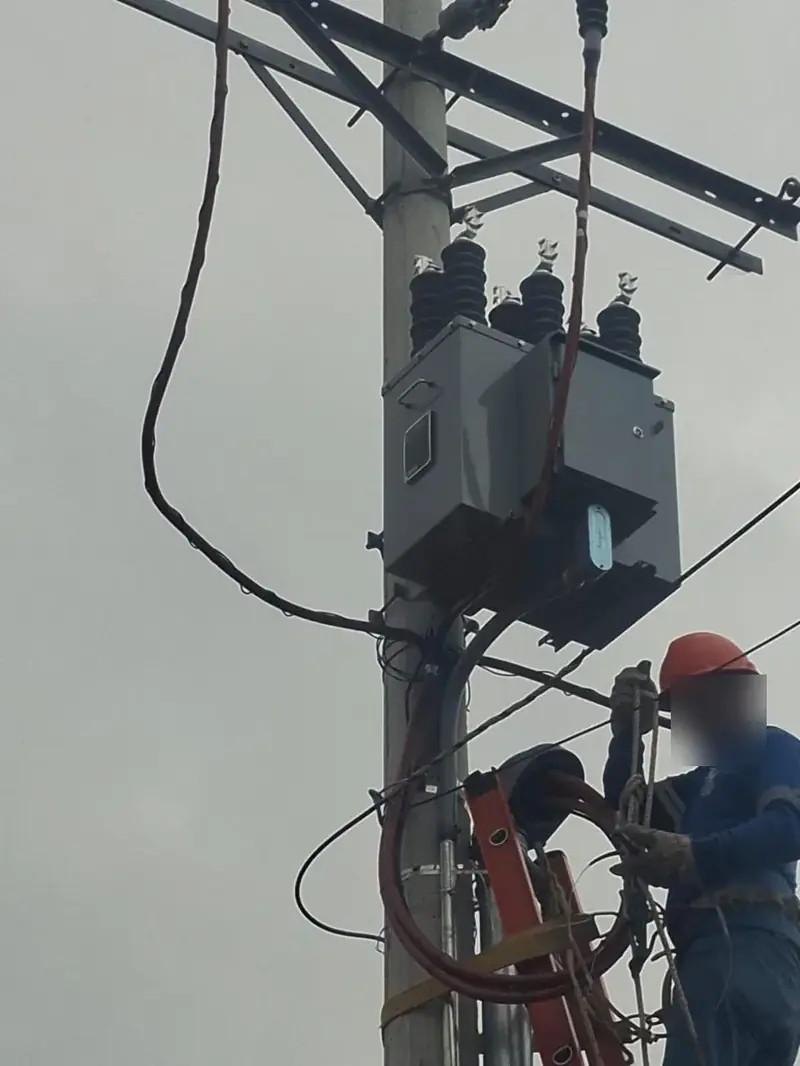 Técnico montando un equipo trifásico de media tensión en un poste